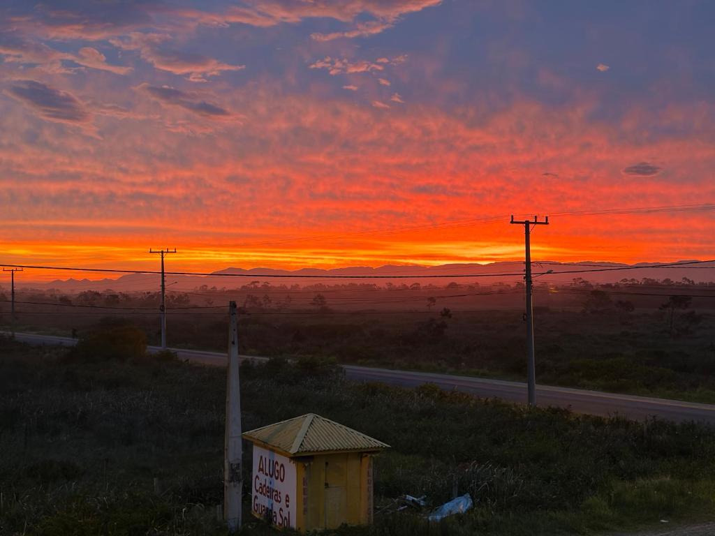 a sunset with a sign on the side of a road at Casa completa para relaxar com a família in Passo De Torres