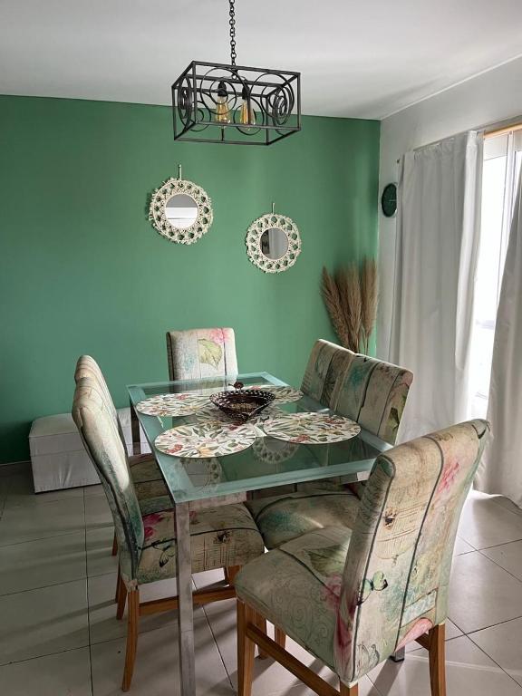 Un comedor con una mesa de cristal y sillas. en Departamento Andy, en Villa Carlos Paz