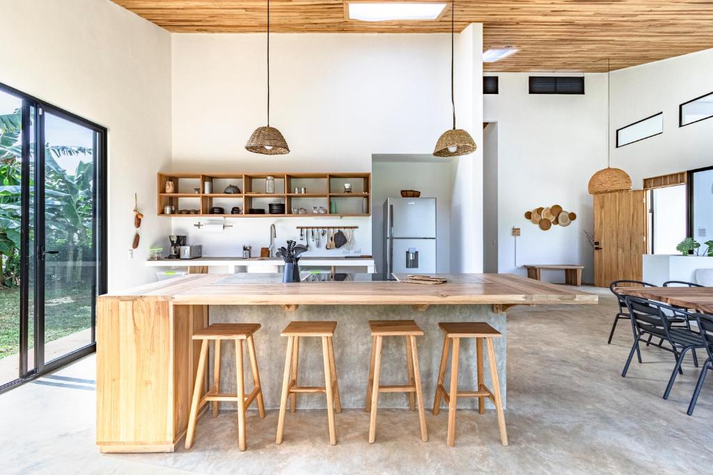 an open kitchen with a large wooden island with bar stools at Private rainforest villa up to 8 guests w jacuzzi near Rio Celeste in Upala