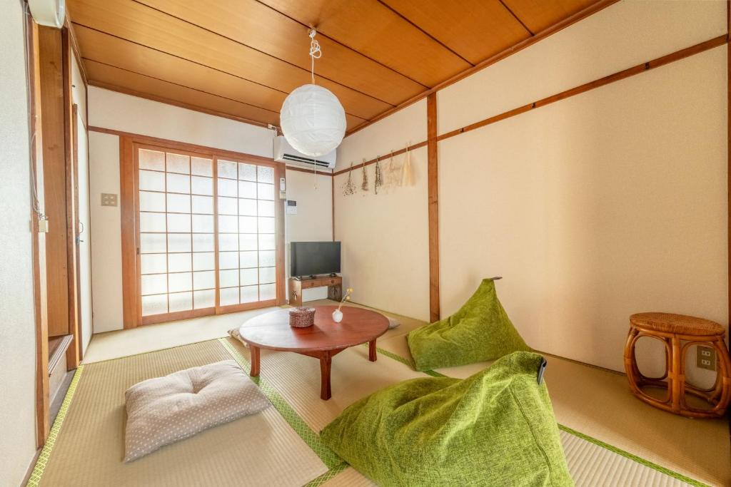a living room with a table and green chairs at GUEST HOUSE Hotori in Otsu