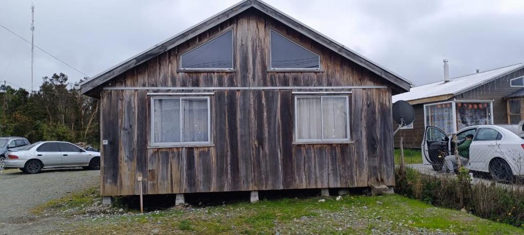a small wooden house with two windows in a yard at Cabaña Quemchi in Quemchi