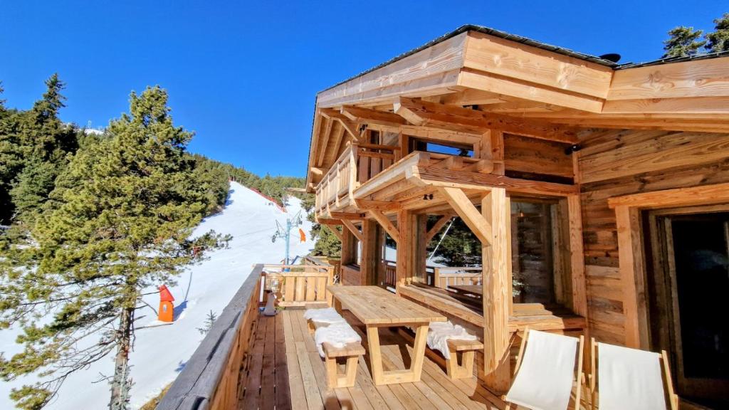 a log cabin with a table and chairs on a deck at Chalet Ski Bob pied de pistes jacuzzi in Font-Romeu