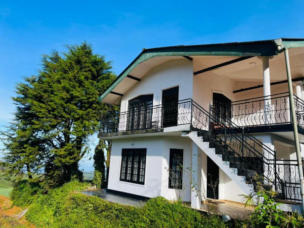 a white building with balconies and a tree at The Crown's lodge Nuwara Eliya in Nuwara Eliya