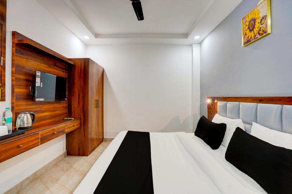 Schlafzimmer mit einem großen weißen Bett und einem TV in der Unterkunft Townhouse Status By Sbg Near Anand Vihar Vaishali Metro Station in Ghaziabad