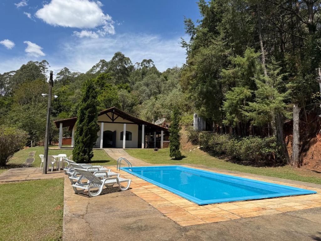 a swimming pool with chairs and a house at Rancho c/ piscina, churrasqueira, natureza e lazer in Batatuba