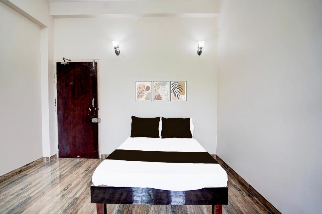 una habitación blanca con una cama con almohadas negras en Hotel O Oyasis.in, en Nagpur