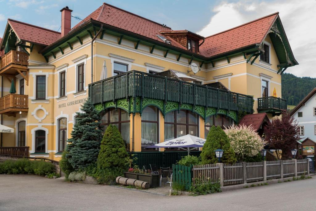 a large yellow house with a red roof at Hotel Goisererhof in Bad Goisern
