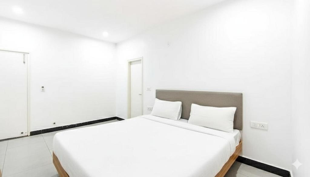 une chambre blanche avec un grand lit avec deux oreillers dans l'établissement Hotel NH7 Near Patiala Chowk Bus stand Zirakpur, à Zirakpur