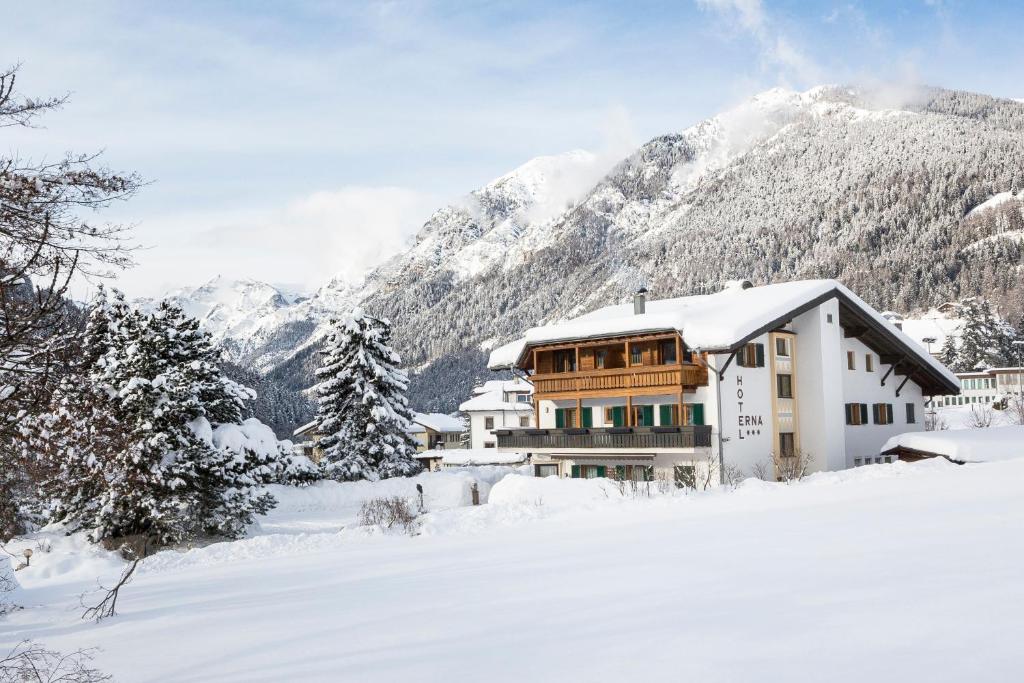 Una casa en la nieve con montañas al fondo en Hotel Erna, en Colle Isarco
