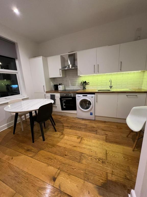 eine Küche mit weißen Schränken und einem Tisch und einer Spüle in der Unterkunft Cozy 1 Bed City Escape in Epsom