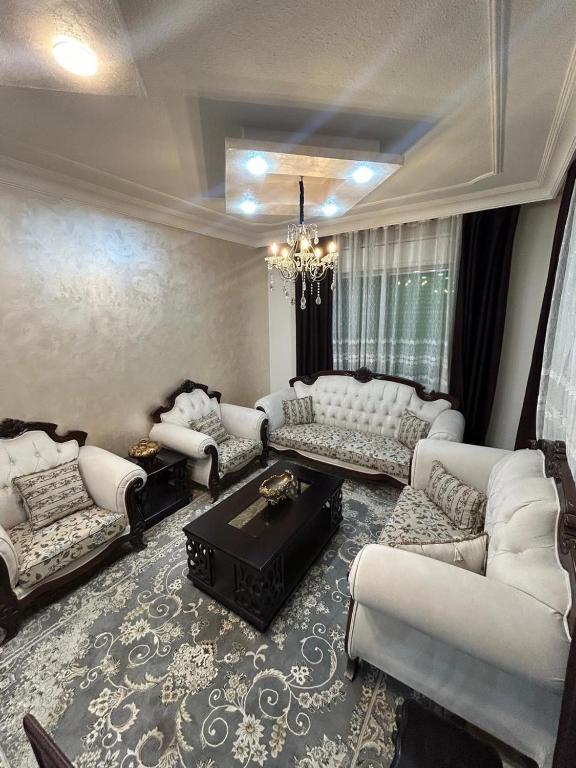 a living room with white furniture and a chandelier at Toum's Apartments 2 in Amman