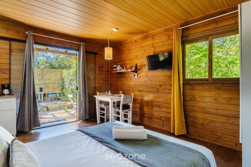 een slaapkamer met een bed, een tafel en een raam bij Chalés Elegantes e Completos em Imbituba - REL in Praia do Rosa