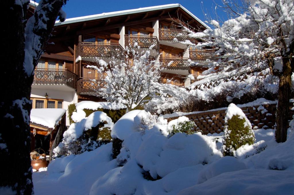 a house covered in snow with trees and bushes at Hôtel Les Côtes, Résidence Loisirs et Chalets in Morzine