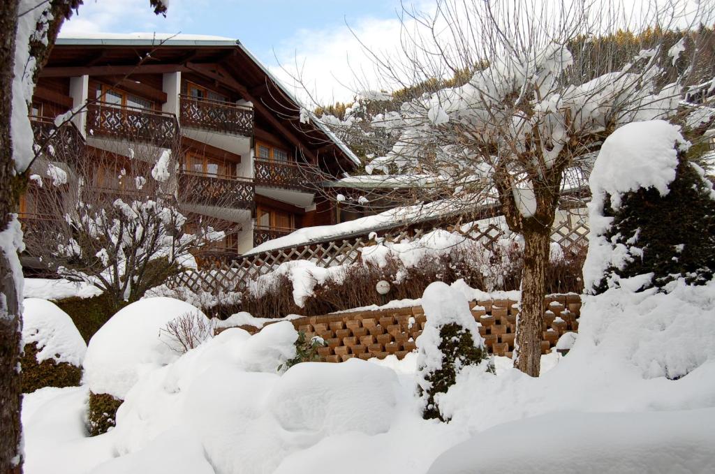 a yard covered in snow with a building in the background at Hôtel Les Côtes, Résidence Loisirs et Chalets in Morzine