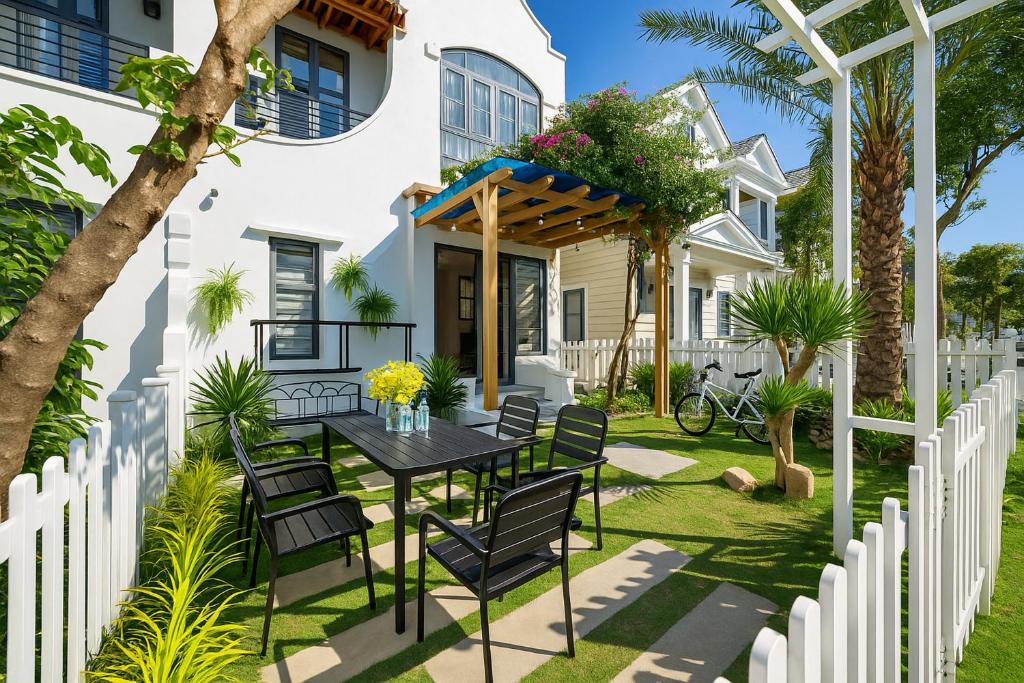 d'une terrasse avec une table et des chaises devant une maison blanche. dans l'établissement The Moon Villa - NOVAWORLD Phan Thiet, à Bình Tú