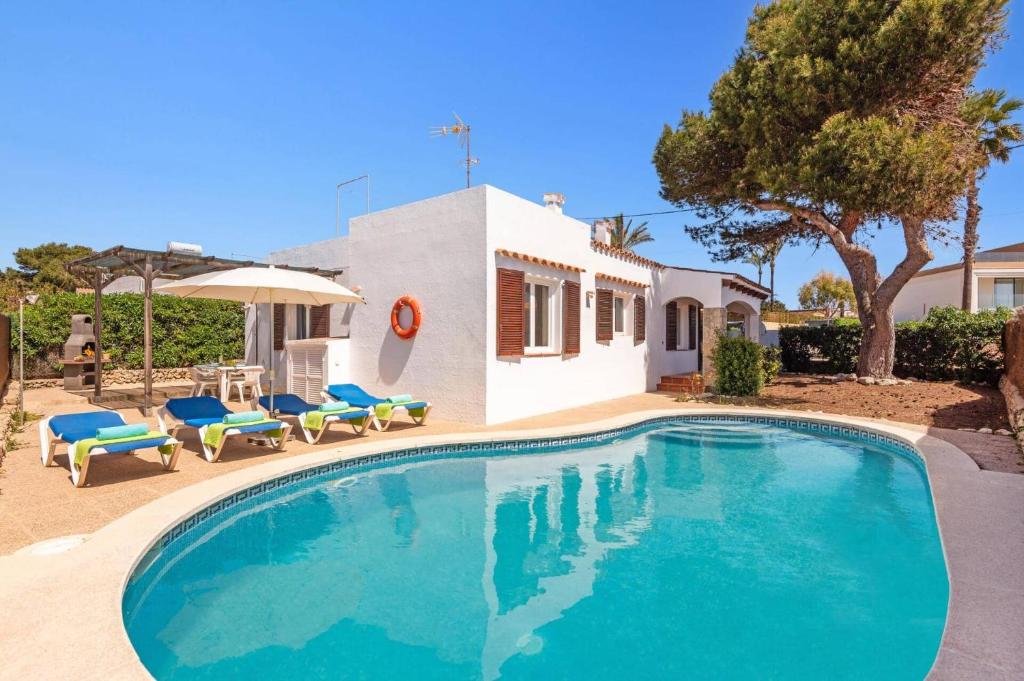 a swimming pool with chairs and a house at Villa Iris Prima by Villa Plus in Punta Prima