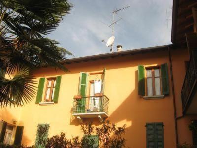 a yellow building with green shutters and a balcony at Casaldo in Gardone Riviera