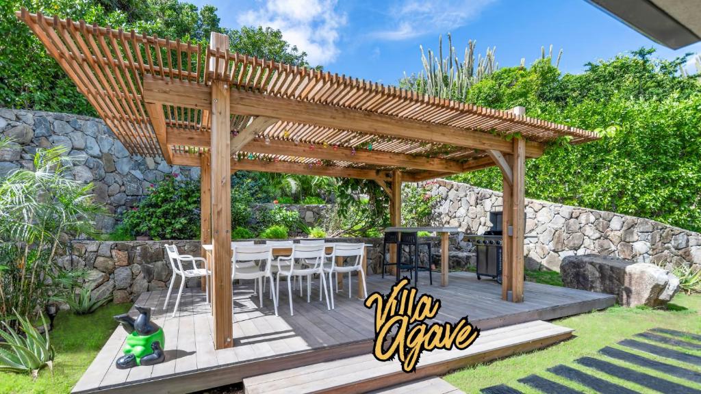 Una terraza de madera con pérgola en un patio. en NEW Villa 3ch et studio independant Jacuzzi vue mer, en Cul de Sac