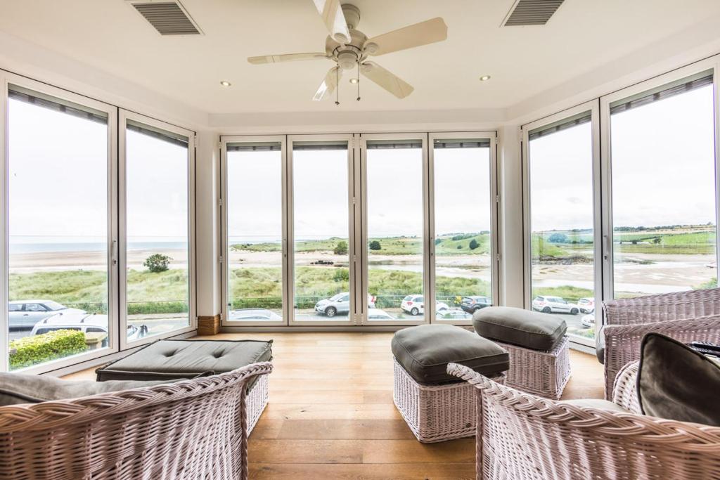 a living room with chairs and a ceiling fan at Seaview Penthouse 1 in Alnmouth