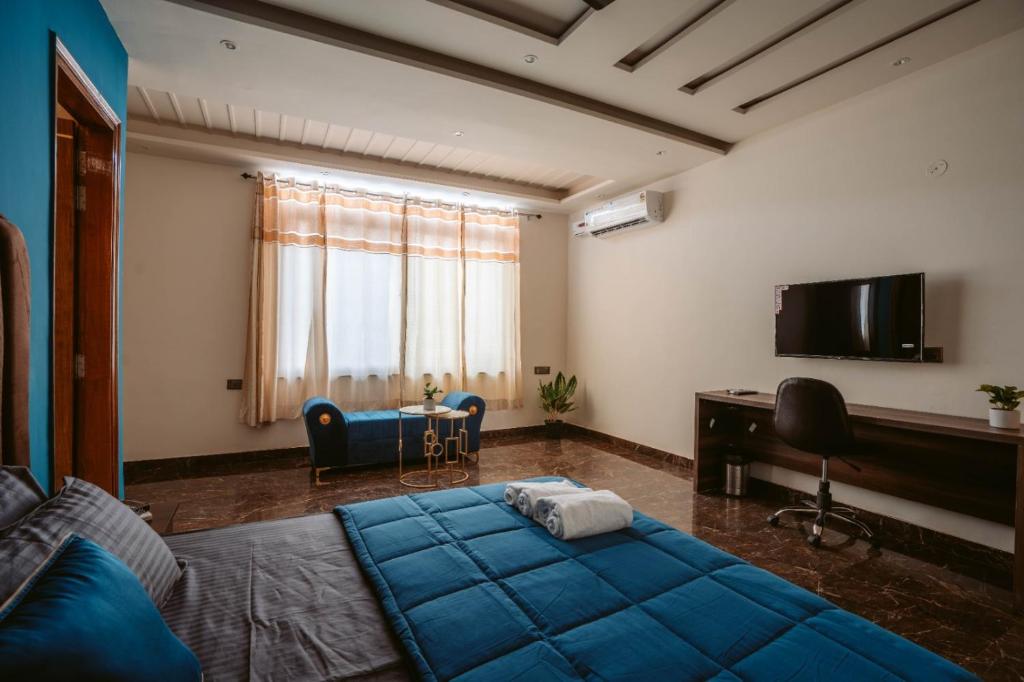 - une chambre avec un grand lit bleu et un bureau dans l'établissement Hotel Golf Sakura, à Gurgaon