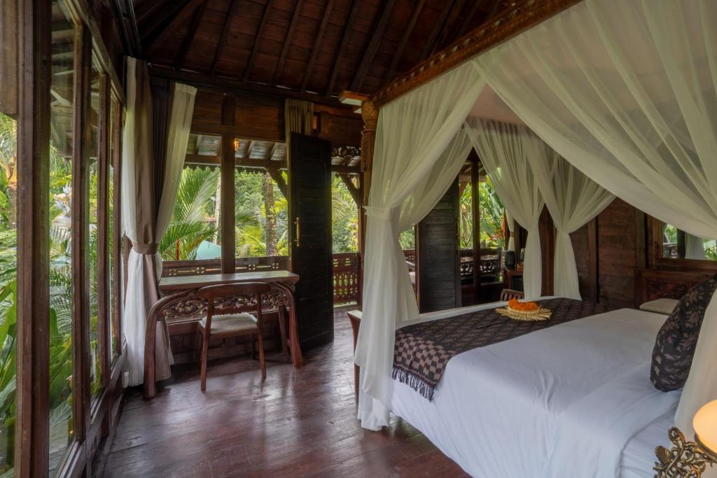 ein Schlafzimmer mit Himmelbett und Schreibtisch in der Unterkunft Aksmi Suites & Villas in Bedahulu