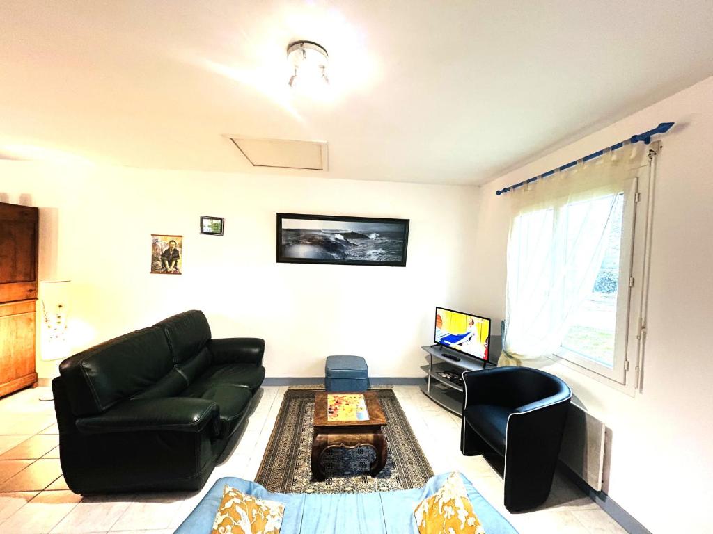 a living room with a couch and a tv at Maison 5 pièces 6 personnes à 10 minutes des plages in Clohars-Carnoët