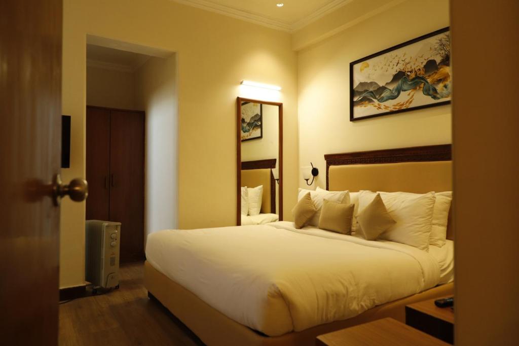 ein Hotelzimmer mit einem großen weißen Bett und einem Spiegel in der Unterkunft Shimla Golf Resorts in Shimla