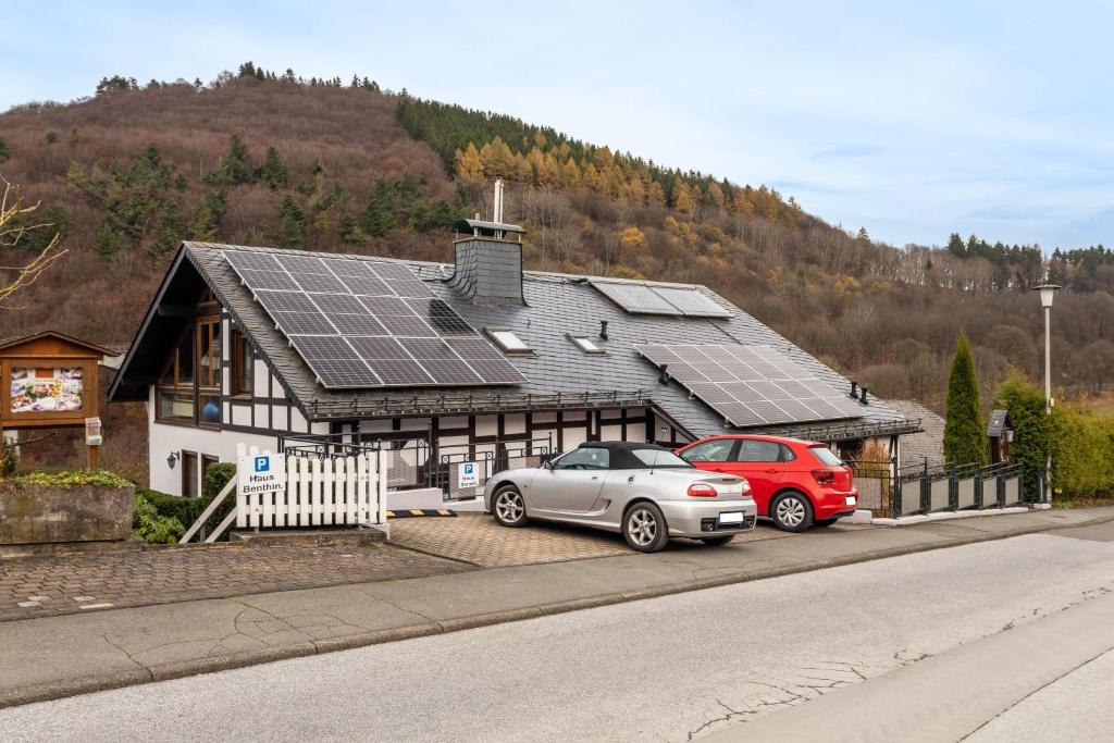 two cars parked in front of a house with solar panels at Haus Stanek in Willingen