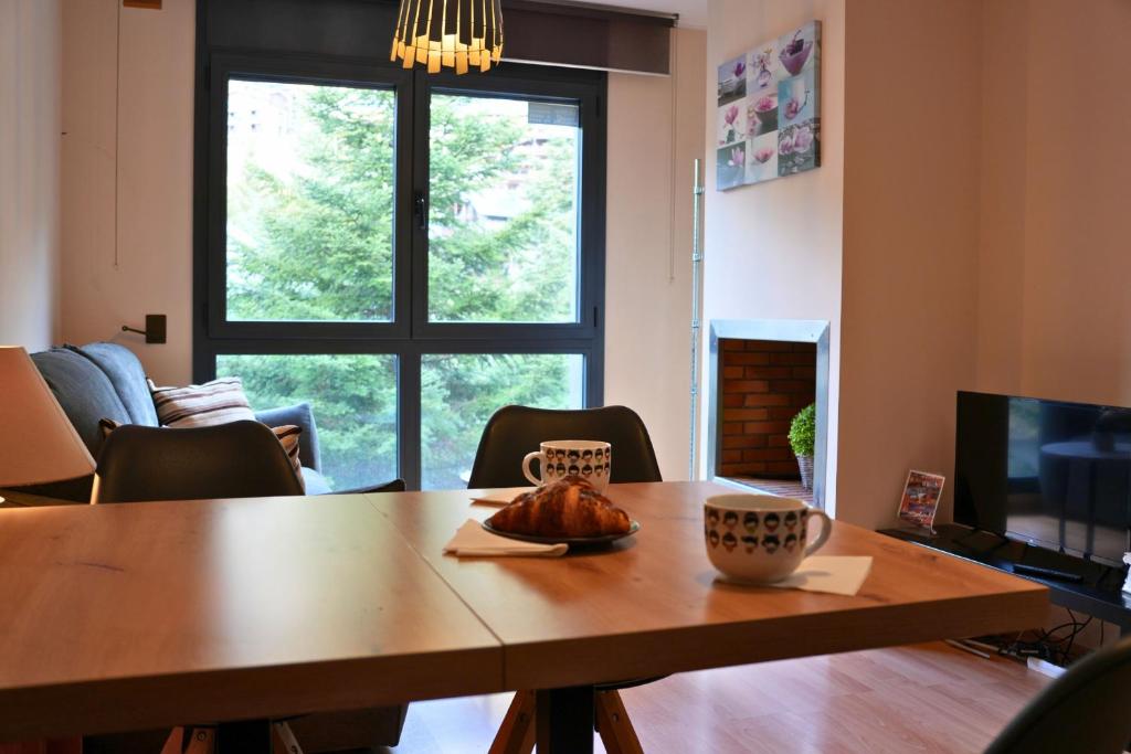 a living room with a wooden table and a television at Soldeu Paradis La Solana in El Tarter