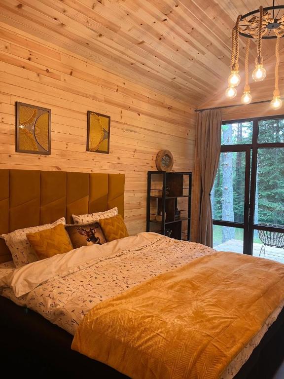 a bedroom with a large bed in a wooden wall at Zarevo Glamping Forest Houses in Skobelevo