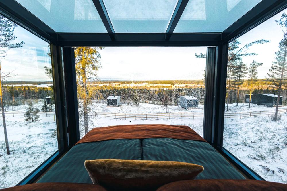 a bedroom with a large window with a view of the snow at Arctic Lumo Resort in Kuusamo
