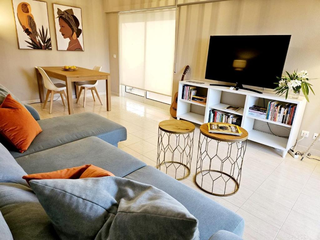 Una sala de estar con un sofá azul y un televisor en Summertime, en Porches