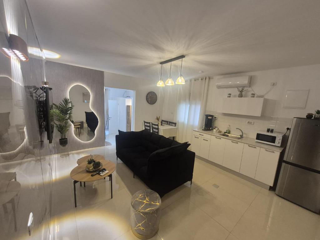 a living room with a black couch and a table at פינוק של סוויטה in Manot