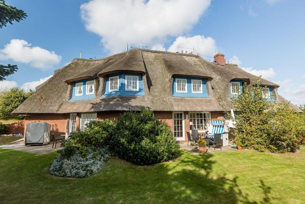 a thatched house with blue windows and a yard at Haus Weesterhuk, Whg 8 Jopi Keitum in Keitum