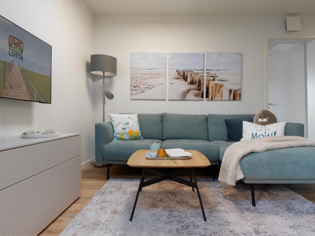 a living room with a blue couch and a coffee table at Küste33-22 Lotta in Tossenserdeich