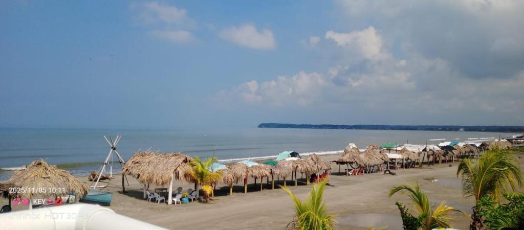 - une plage avec un bouquet de parasols en paille et l'océan dans l'établissement El legado de las olas, à Carthagène des Indes