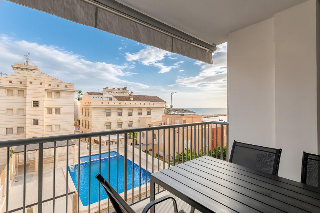 einen Balkon mit einem Tisch und einem Pool in der Unterkunft Mar 4 en Santa Pola in Santa Pola