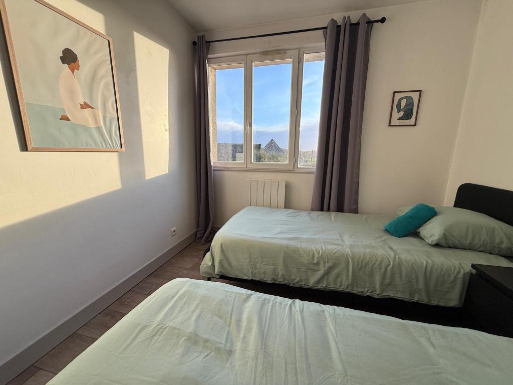 a bedroom with two beds and a window at Trois pièces vue campagne à Bâlines in Balines