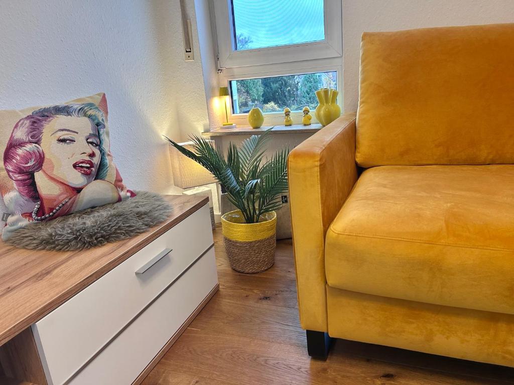 ein gelber Stuhl in einem Zimmer mit einem Bild einer Frau in der Unterkunft Ferienwohnung Karma in Kressbronn am Bodensee