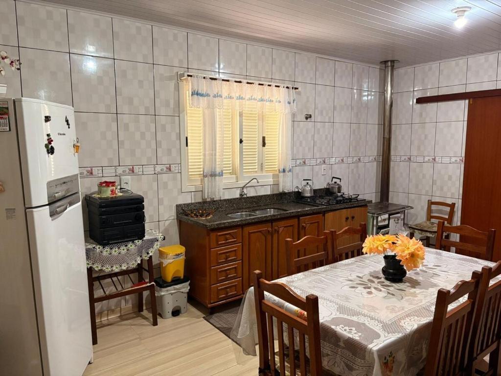 a kitchen with a table and a refrigerator at Omma's Haus - Casa de Vó perto de Gramado in Morro Reuter