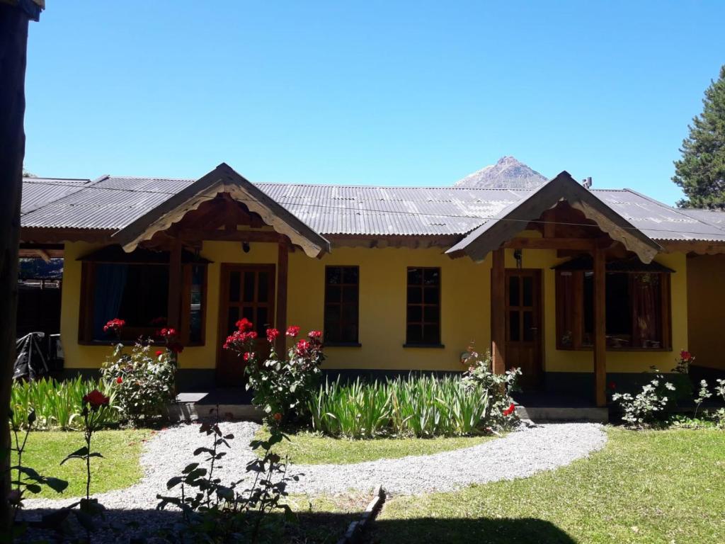a yellow house with flowers in front of it at Las Rosas EH in El Hoyo