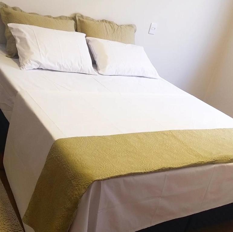 a bed with a yellow and white blanket on it at Loft 03 - Zona Sul Prox UMC, Pátio Vinhedos e Shopping in Uberlândia