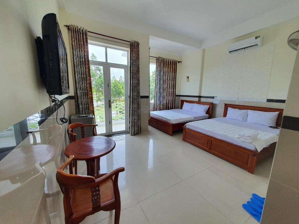 una camera con due letti, un tavolo e una televisione di Motel Bờ Kè a Ba Ria