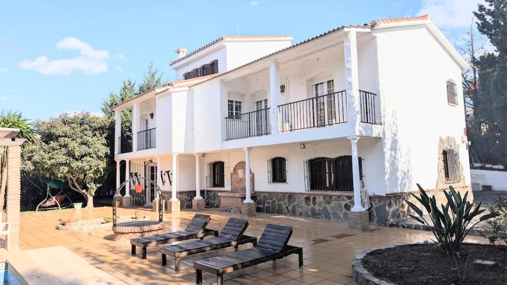 a white building with benches in front of it at Villa Mona Private pool and barbecue in Malaga in Málaga