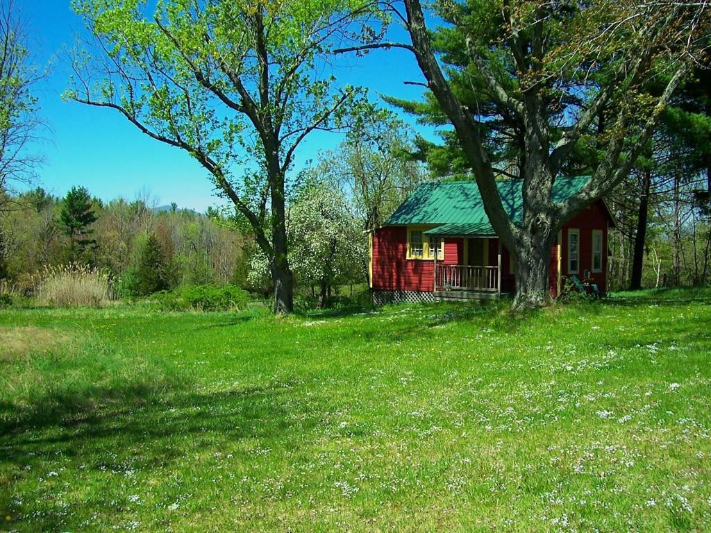 une cabine rouge dans un champ avec un arbre dans l'établissement Clove Cottages, à Accord
