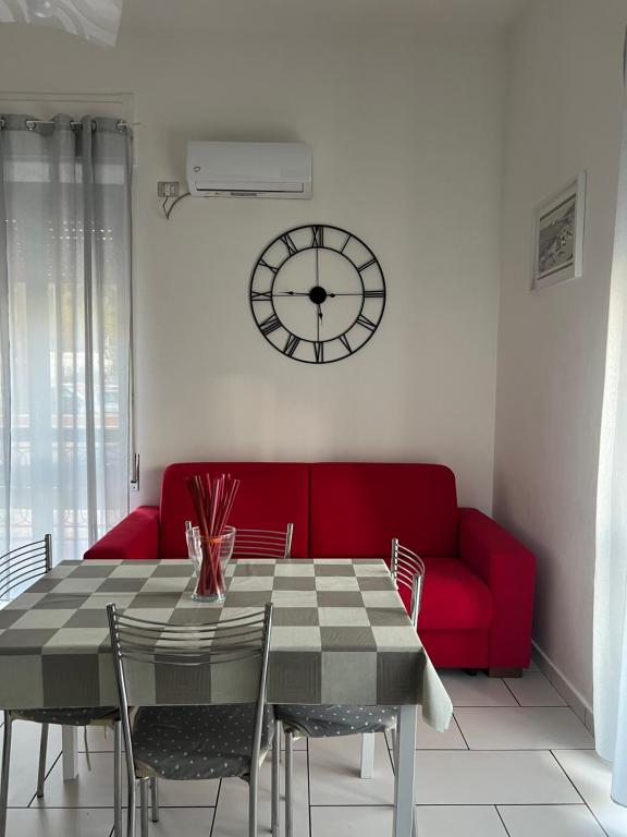 a dining room with a red couch and a clock at A casa di Rita in Agropoli