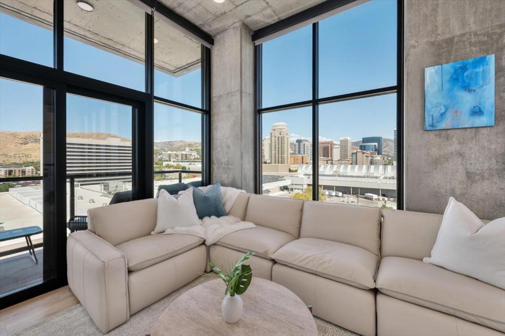 ein Wohnzimmer mit einem weißen Sofa und großen Fenstern in der Unterkunft Luxury 2BR 2BA Penthouse-Pool, Gym, Pkg, Views! in Salt Lake City