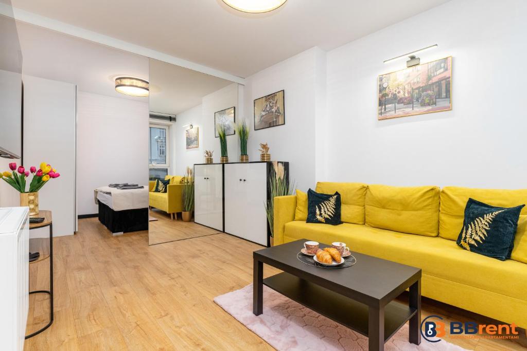 ein Wohnzimmer mit einem gelben Sofa und einem Tisch in der Unterkunft Apartament pod Prezydentem in Bielsko-Biała