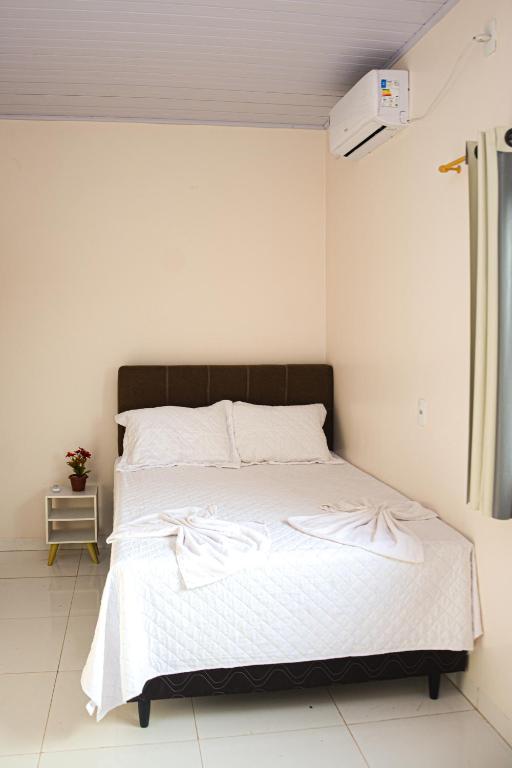 a bedroom with a white bed with a black headboard at Suíte no cidade Jardim in Parauapebas