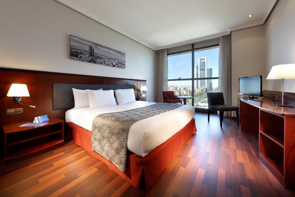 a hotel room with a bed and a desk and a television at Crisol Vía Castellana in Madrid